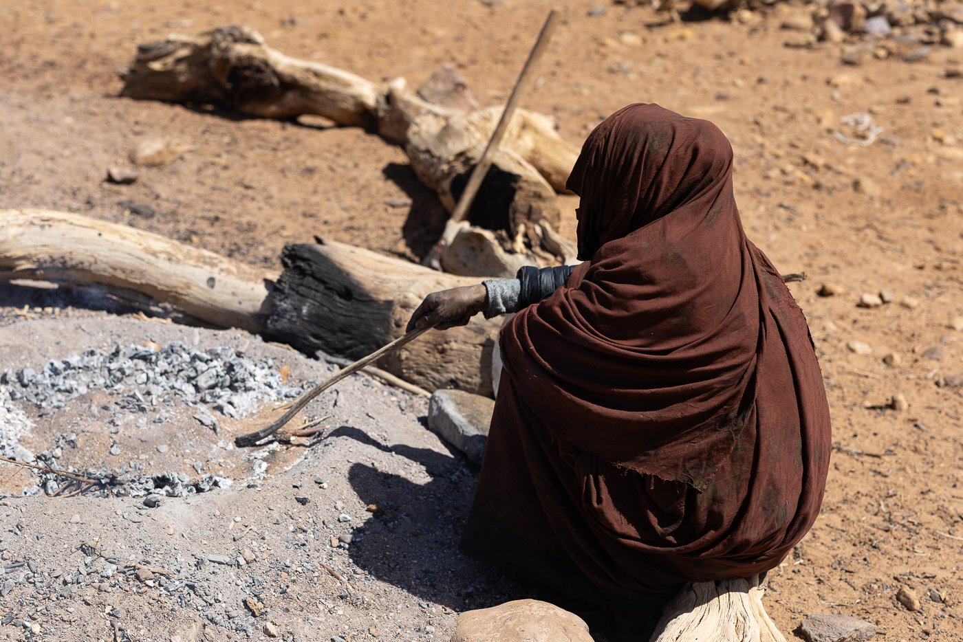Berber guides preparing a fire-cooked meal at a desert camp.
